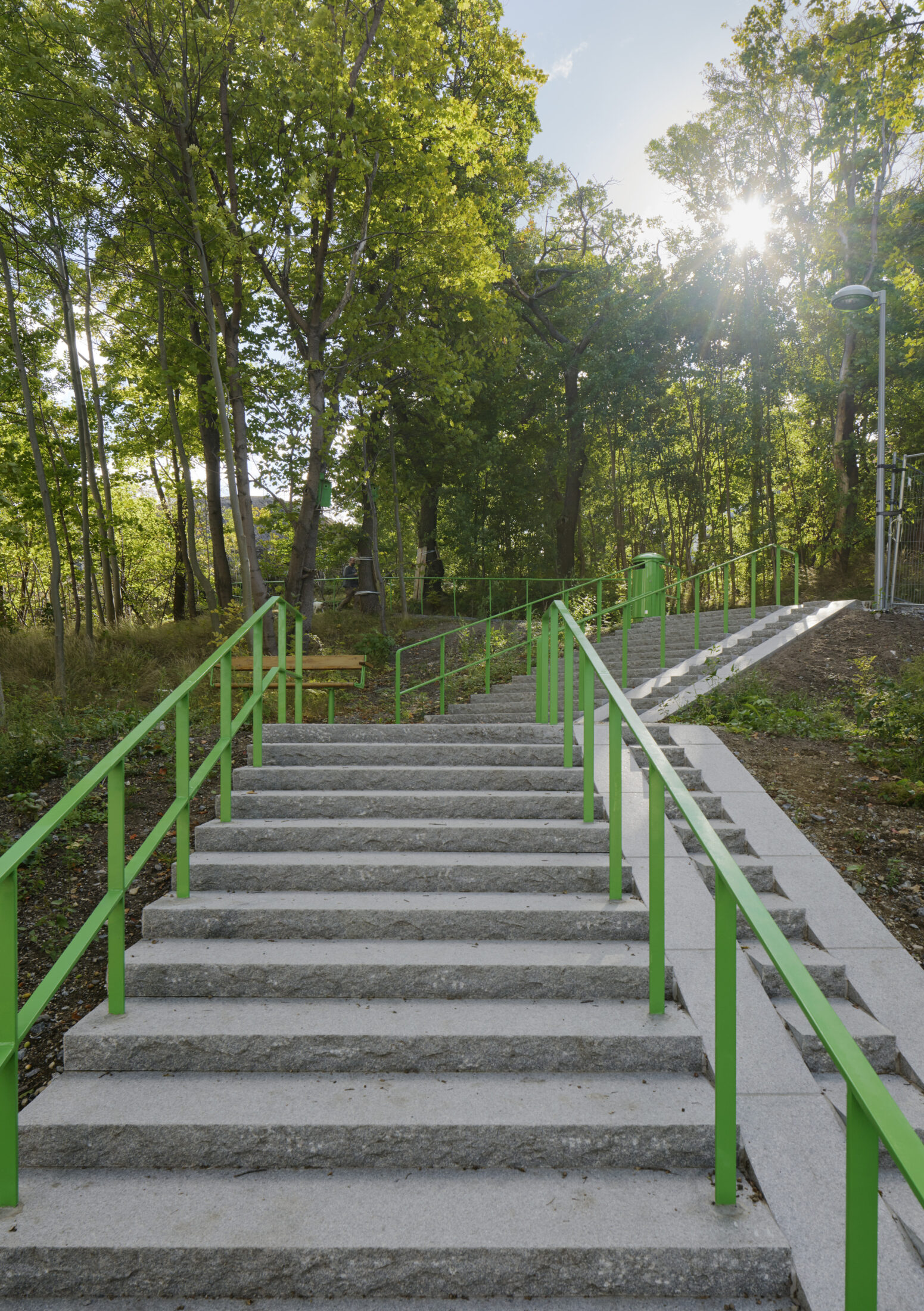 Stentrappa leder vägen upp i Årstabergsparken. Gröna trappräcken på var sida.